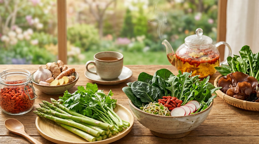 A wooden table set with fresh spring vegetables, herbs, ginger, asparagus, leafy greens, and a glass teapot — representing TCM liver-nourishing foods for spring wellness.
