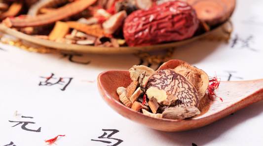 Traditional Chinese herbs on wooden spoon and plate, used in seasonal skincare and wellness rituals