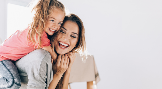 Mother and young daughter smiling and hugging at home, representing busy moms who need a simple, quick skincare routine.