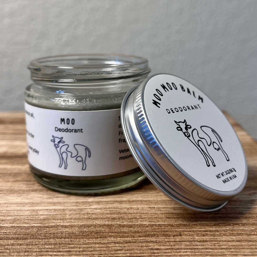 Moo Moo Balm Natural Deodorant in glass jar with aluminum lid on wooden surface — tallow-based, aluminum-free, magnesium deodorant for sensitive skin, made in USA.
