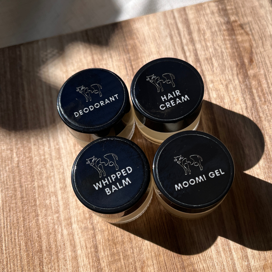 Moo Moo Balm mini collection featuring Deodorant, Hair Cream, Whipped Balm, and Moomi Gel jars on a wooden surface, natural light and handcrafted presentation.